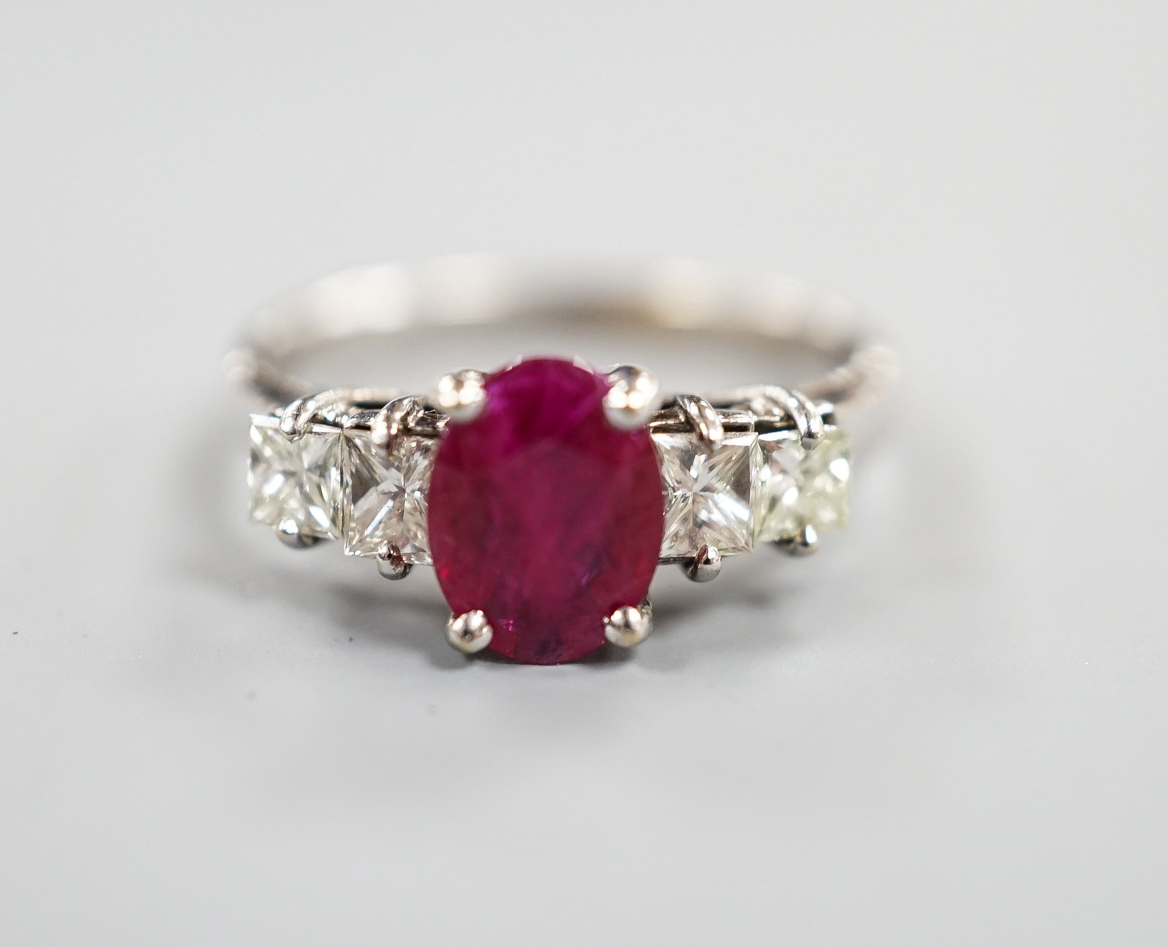 A modern 750 white metal single stone ruby and four stone princess cut diamond set half hoop ring, size M, gross weight 3.2 grams.